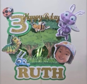 Bug-themed birthday cake topper with the name Ruth